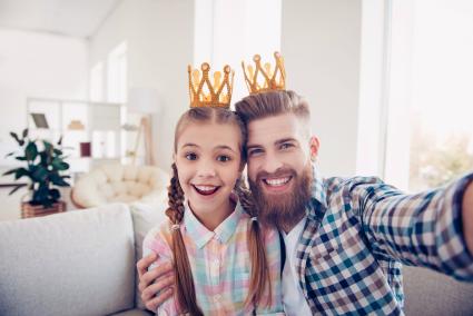 Niño lindo y elegante papá con coronas mientras se toma un selfie