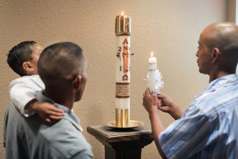 Los hombres encienden velas bautismales en la iglesia