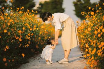 Madre feliz con bebé en campo de flores de cosmos amarillo 